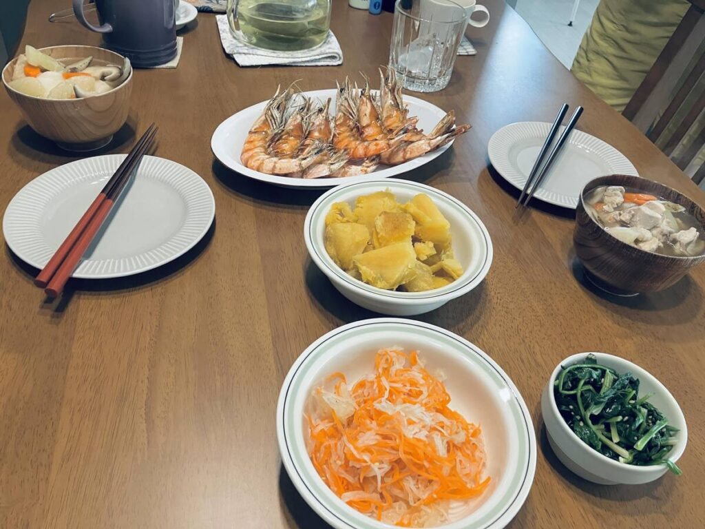 落ち着いた食卓に並ぶ、煮物や焼き海老などの家庭料理