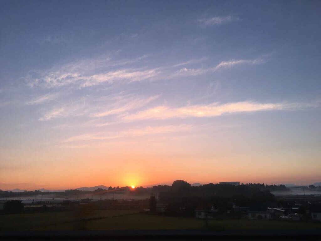 地平線に沈む夕日の風景|夕焼けの空を眺めながら一日を静かに振り返る内省の時間をイメージした夕暮れの景色