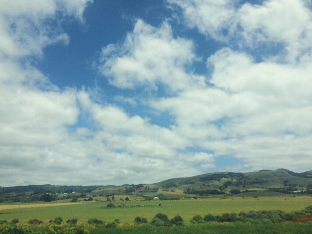 雲が浮かぶ空と緑の丘の風景｜自然の広がりの中で自分をそのまま受け入れる自己受容の時間をイメージした景色