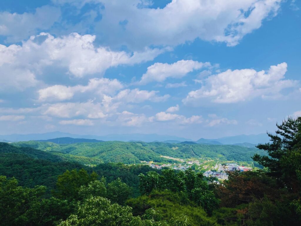 雲が広がる空と緑の丘の風景|広い空を眺めながら心をゆるめる内省の時間をイメージした自然の景色